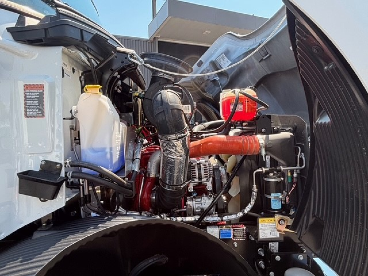 Mack MD7 engine bay showing coolant reservoir, air intake, hoses, and various components.