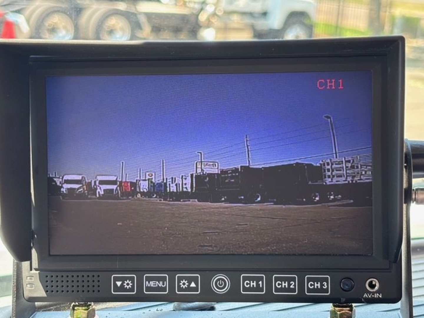 Mack MD7 truck cab interior monitor displaying CH1 camera view with vehicles in lot.
