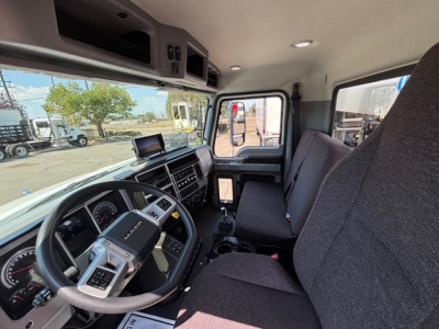 Mack MD7 cab interior showing steering wheel, dashboard, and seating from driver side.