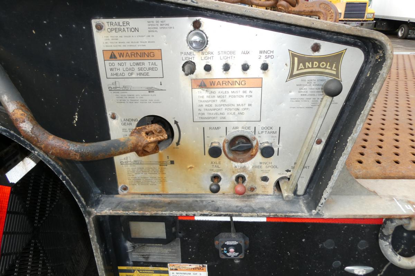 Landoll 930D NGL trailer control panel with warning labels and switches, rusted inlet hose, Landoll logo plate.