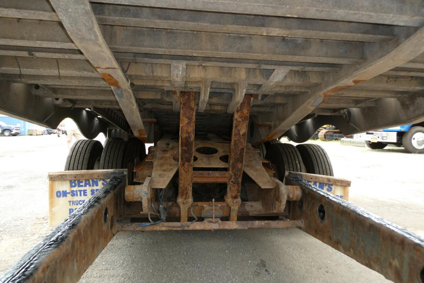 Rear underside view of a Landoll 930D NGL trailer showing dual rear axles, rusty frame components, and leaf spring suspension.
