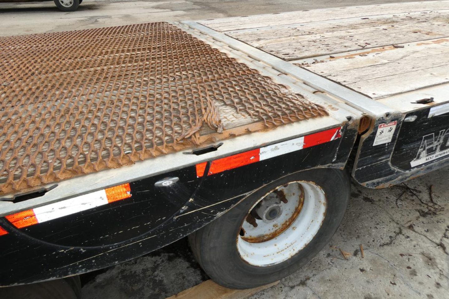 Landoll 930D NGL trailer wheel and rear deck showing worn metal grading and LED reflectors along the edge.