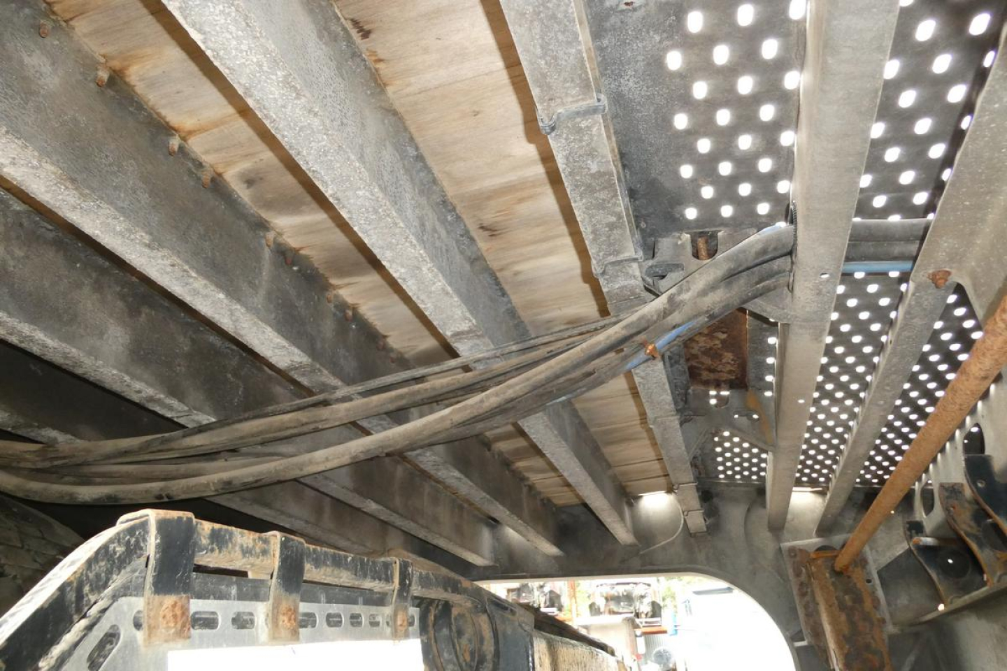 Trailer interior showing structural metal beams and hoses under a Landoll 930D NGL trailer.