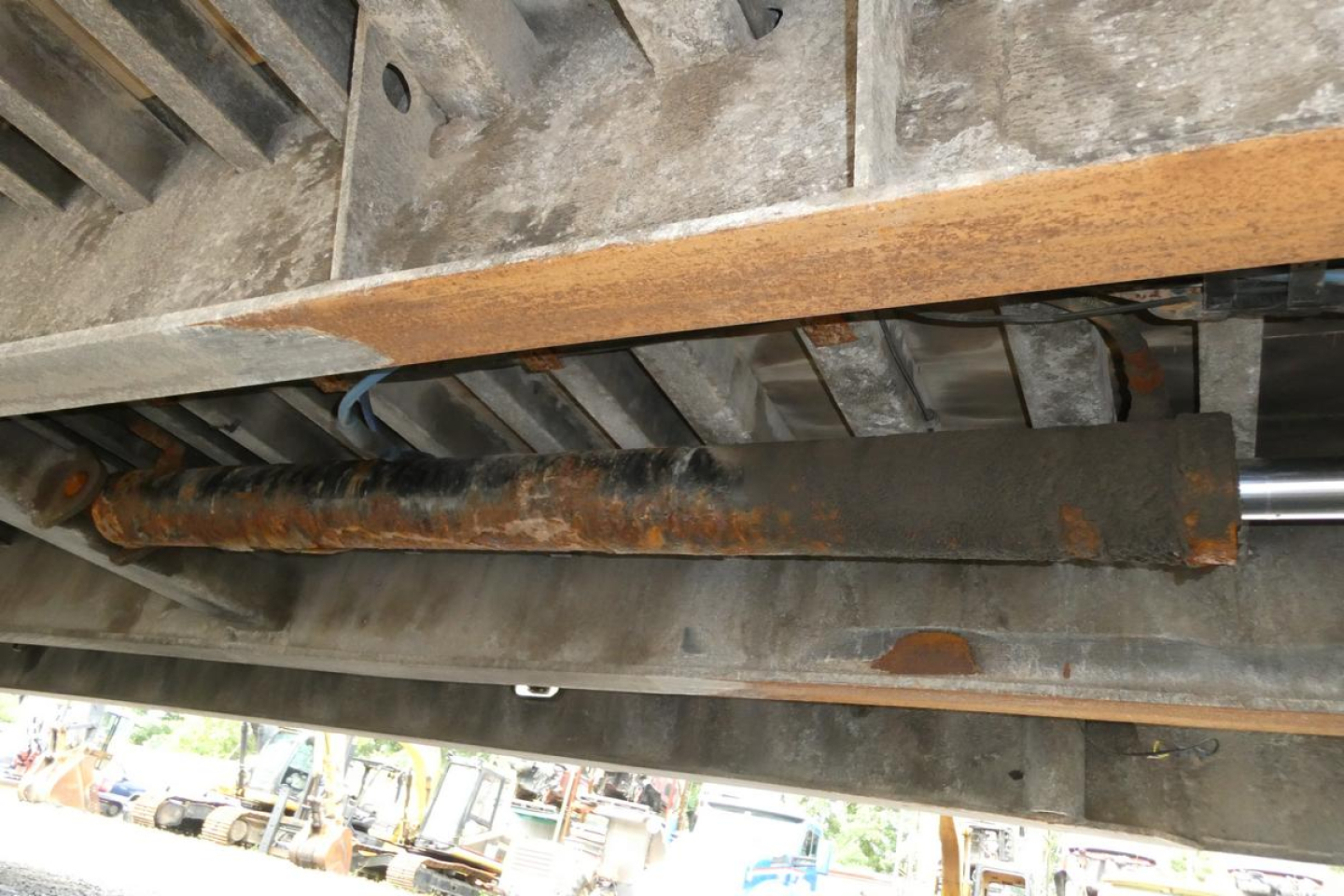 Landoll 930D NGL trailer undercarriage showing hydraulic ram and metal beams with rust spots, side view inside frame.