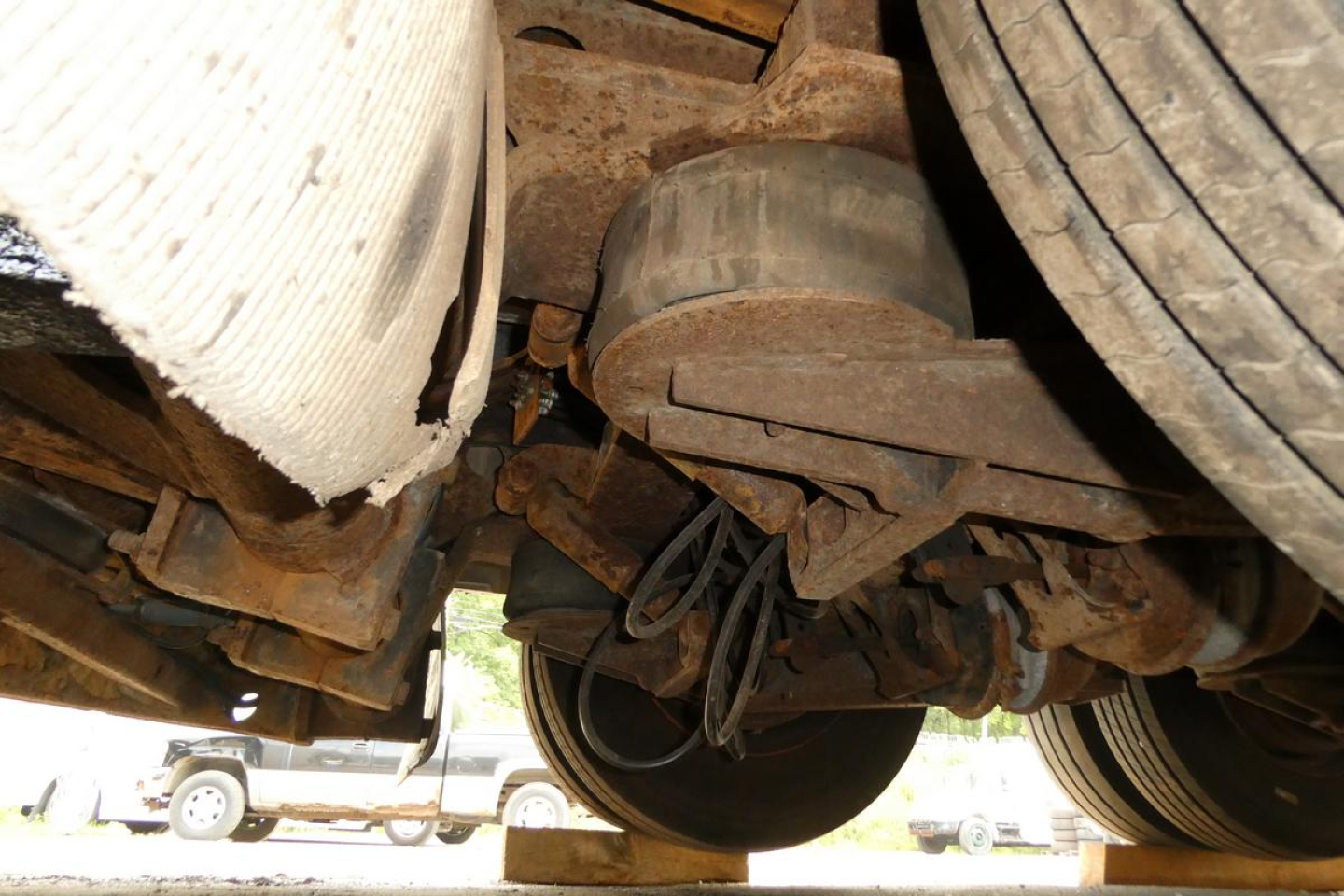 Rear underside of Landoll 930D NGL trailer showing suspension, leaf springs, axle, and wheel hub area with hoses and frame components.