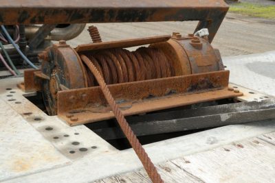 Winch drum and steel cable on trailer hook-up showing rusted winch housing and coil rope.