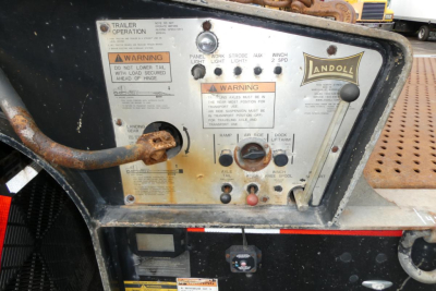 Landoll 930D NGL trailer control panel with warning labels and switches, rusted inlet hose, Landoll logo plate.