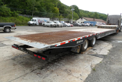 NGL flatbed trailer showing 930D model, steel grated deck, rear underride guards, and multiple axles in a used condition.