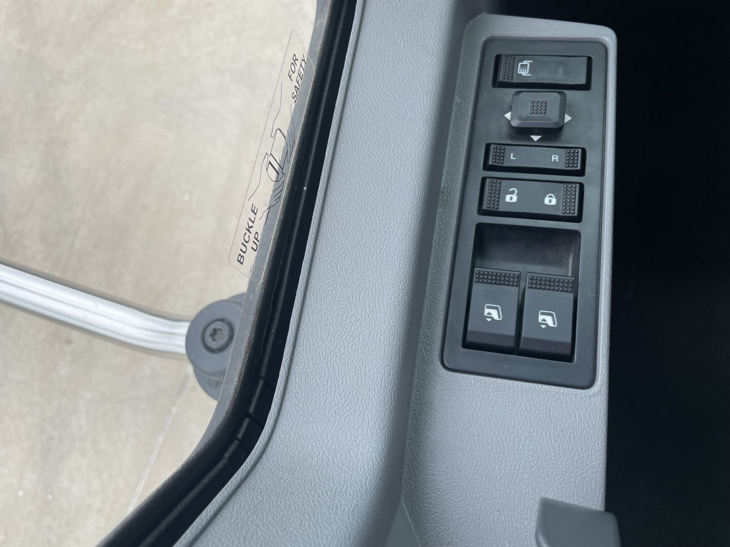 Truck interior: door control panel with window/lock switches and mirror controls adjacent to door frame; part of a 2025 Mack MD7 listing.