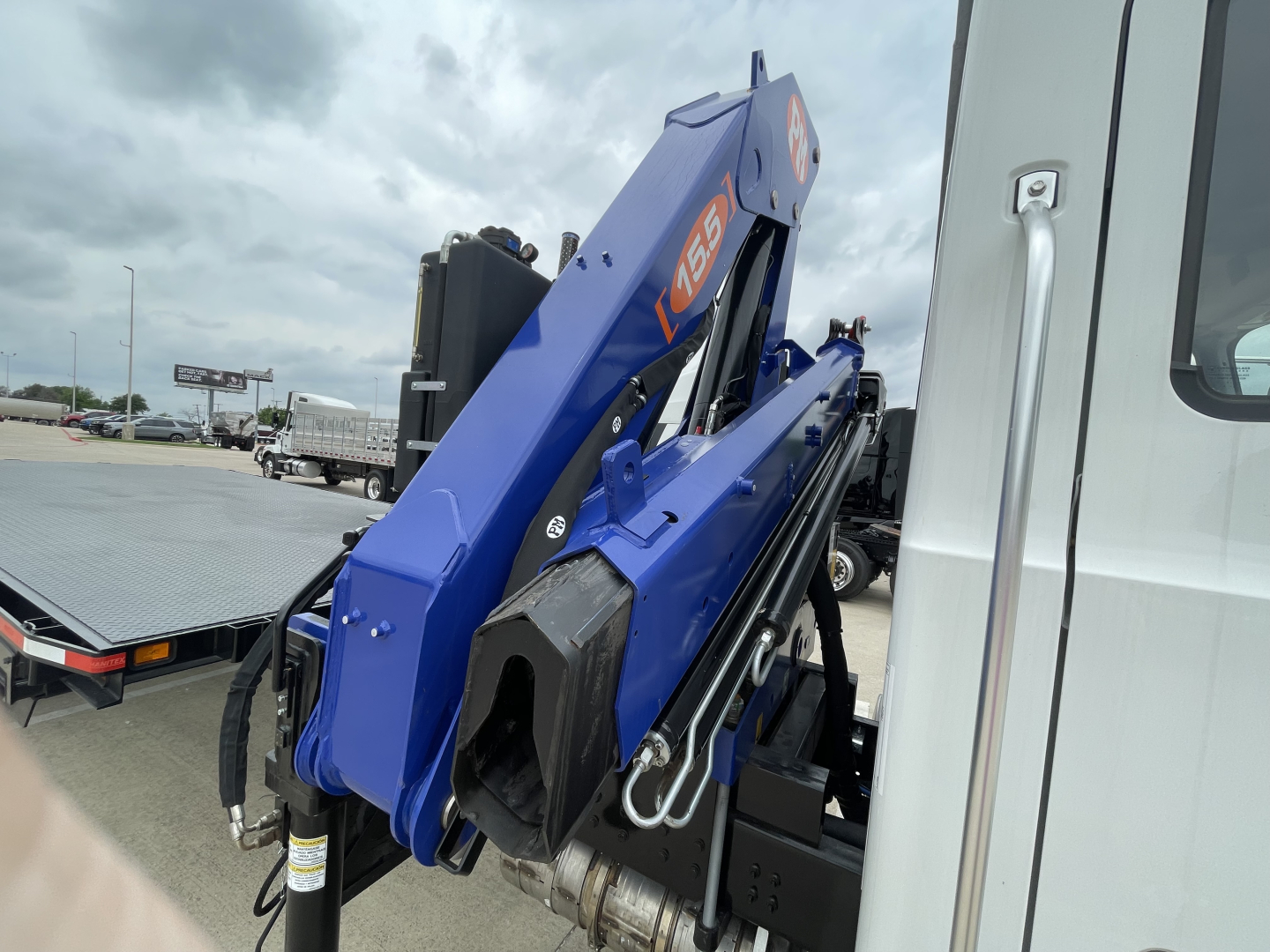 Mack MD7 boom truck arm in blue folded on a white cab; visible labels include 65 and hydraulic components