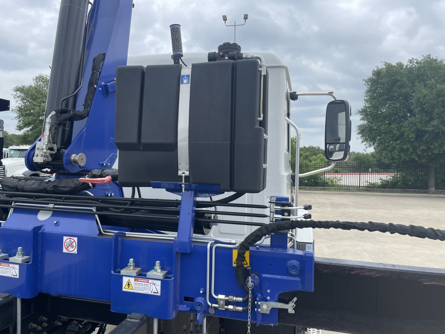 Mack MD7 boom truck cab with black fuel/def tank and blue chassis showing wiring and hydraulic lines.