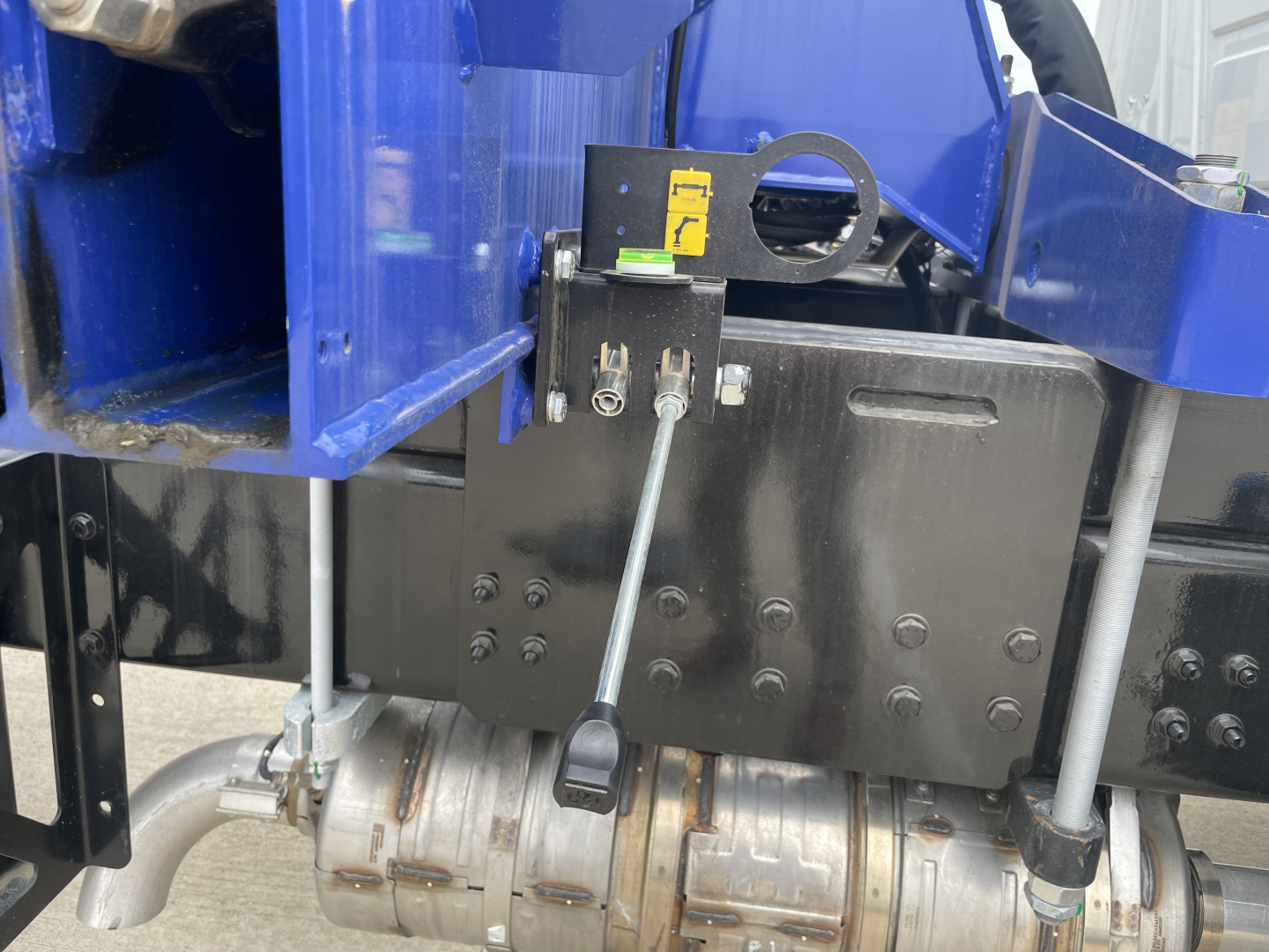 Mack MD7 boom truck engine bay area with hydraulic control valve, hoses, and black metal mounting plate visible.