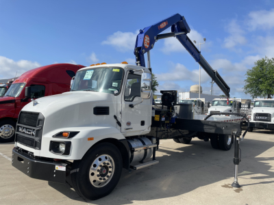 Mack MD7 boom truck showing hydraulic boom and flatbed with stabilizer leg visible.