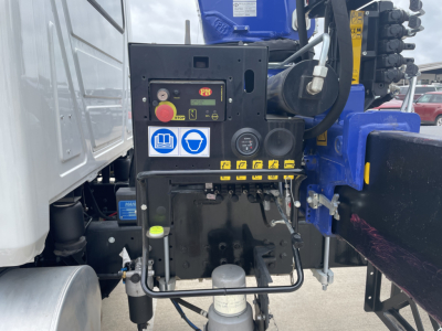 Mack MD7 boom truck cab area showing control panel and hydraulic levers with warning stickers.