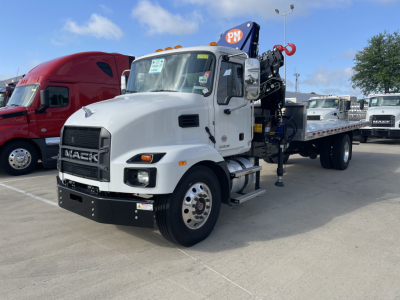Mack MD7 truck with a mounted crane boom in a dealership lot, front-left view showing white cab, black grille, and crane arm folded over flatbed.
