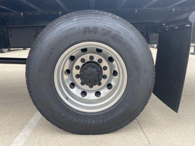 Mack MD7 truck wheel and tire showing aluminum rim and lug nuts, undercarriage frame visible.