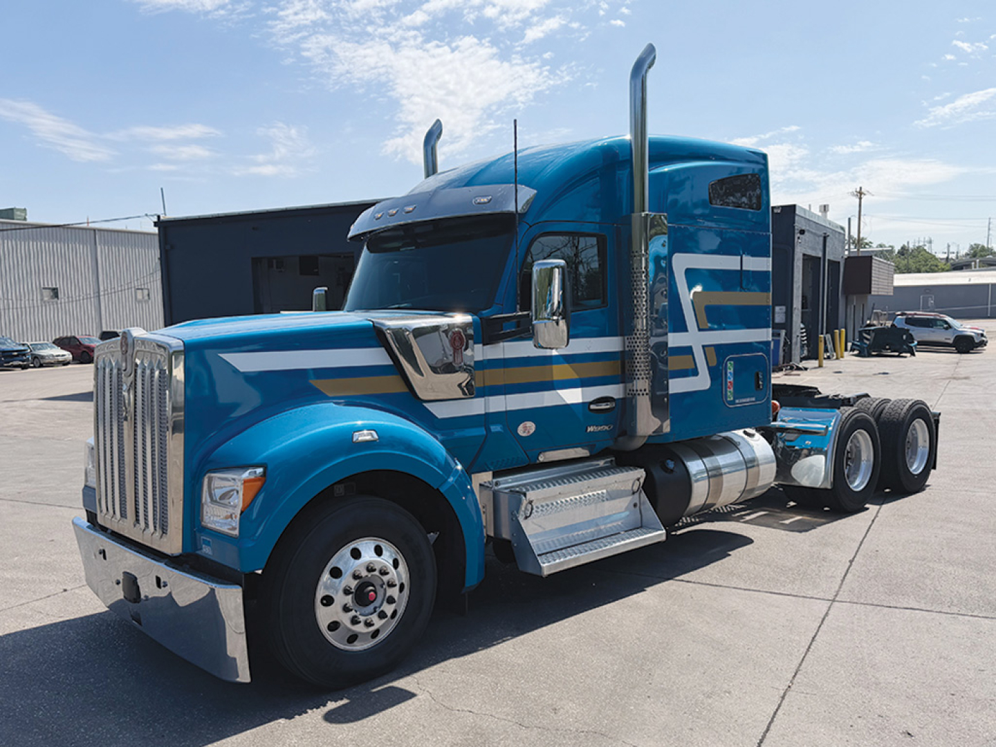 Kenworth W-990 truck in blue with chrome exhaust stacks and sleeper cab; visible text on truck includes no explicit model text readable; front grille; fuel tanks and steps; side decals