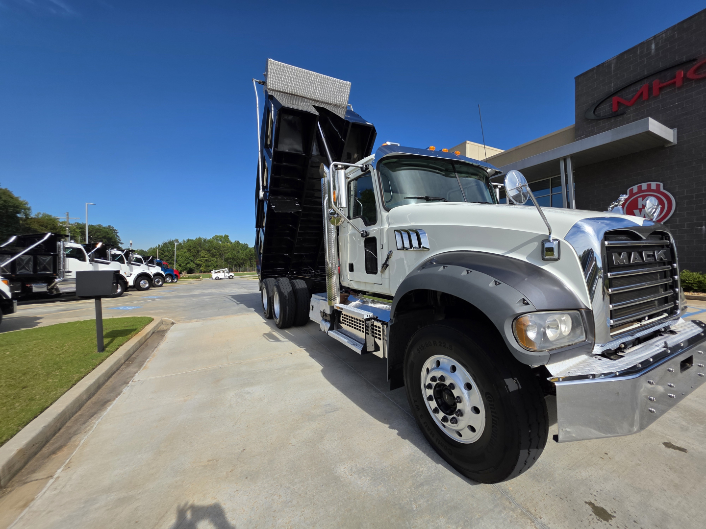 Grey 2022 Mack Granite dump truck with raised dump bed, front chrome grille, large tires, and side steps. VIN 1M2GR2GC3NM025244 visible on listing information board.