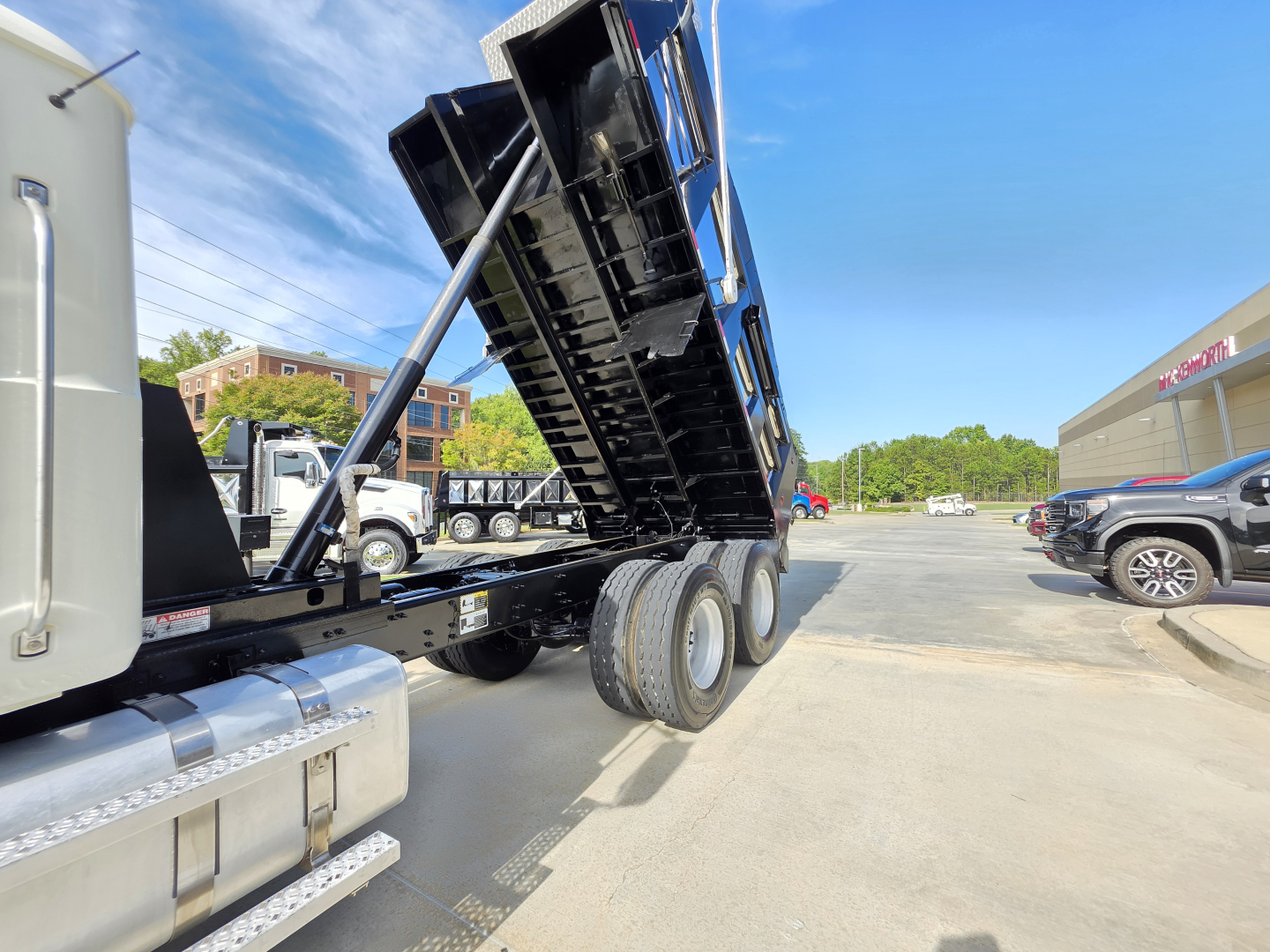 Dump truck bed in raised position on a 2022 Mack Granite, side view showing chassis and dual rear axles.