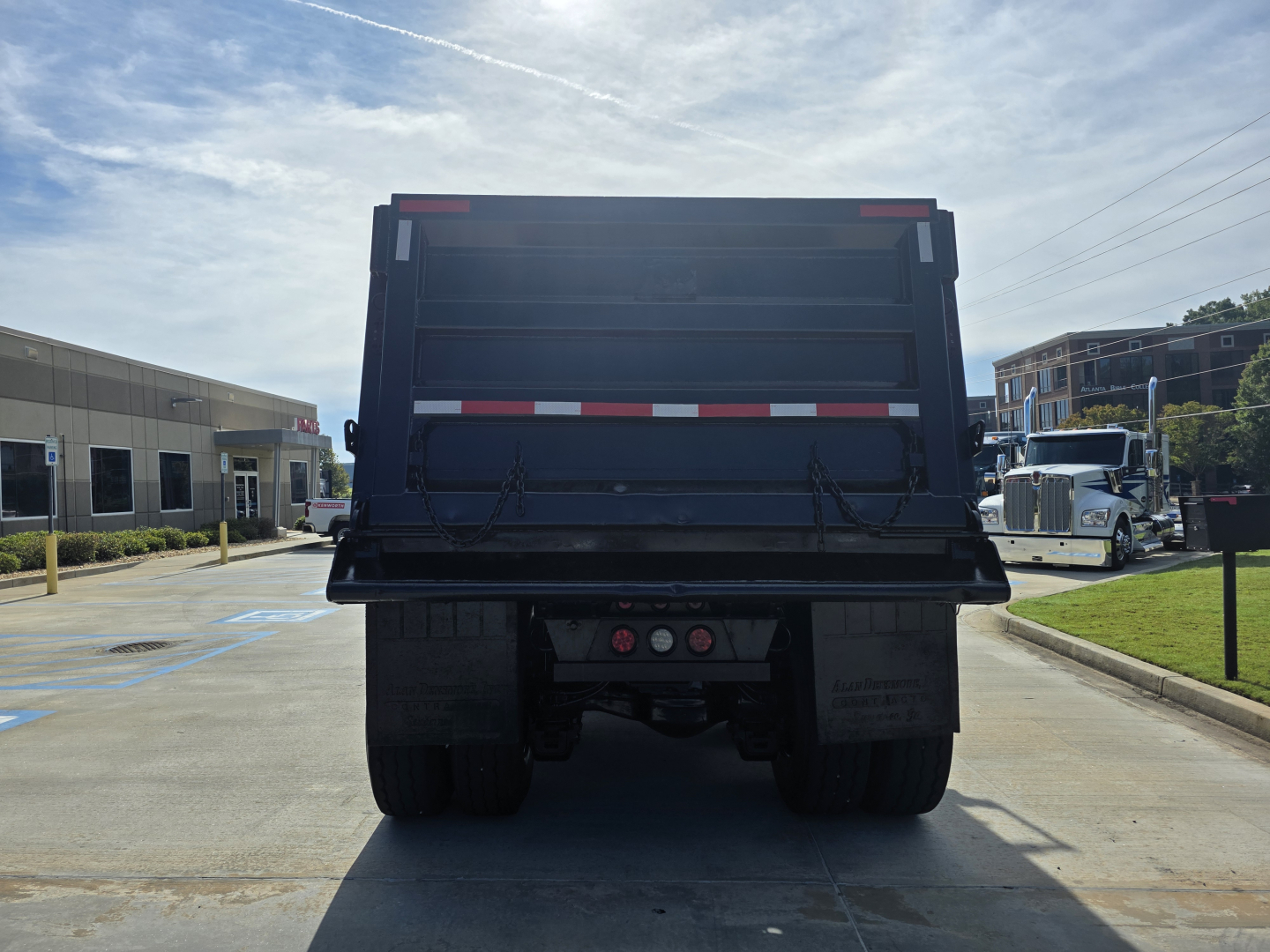 Dump truck bed rear view of a 2022 Mack Granite showing the tailgate, bumper, and dual rear wheels.