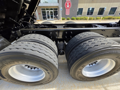 Dual rear truck tires and suspension undercarriage of a 2022 Mack GRANITE dump truck showing tandem axle, chassis rails, and leaf springs.