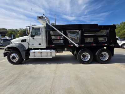 Truck side profile showing a 2022 Mack GRANITE dump truck with black dump bed, white cab, metal steps, dual rear axles, and hydraulic dump mechanism.