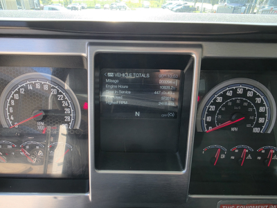 Mack Granite truck dashboard close-up showing instrument clusters and a central digital display with vehicle totals including mileage, engine hours, and uptime.