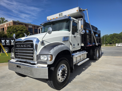 Mack Granit(e) dump truck in white and chrome front grille view showing side steps and dump body.