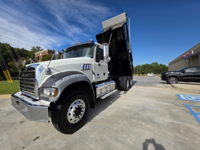Mack Granite dump truck in service showing front left angle with raised dump bed and chrome bumper.