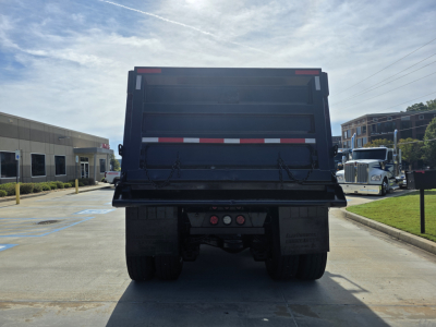 Dump truck bed rear view of a 2022 Mack Granite showing the tailgate, bumper, and dual rear wheels.