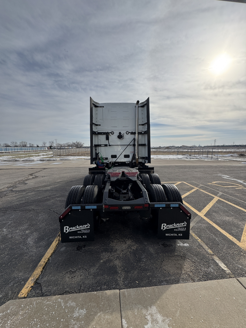 Rear view of a Mack PR64T76H truck tractor chassis in an empty lot; visible mud flaps show Buckner truck logos; no cab, fifth wheel area present.