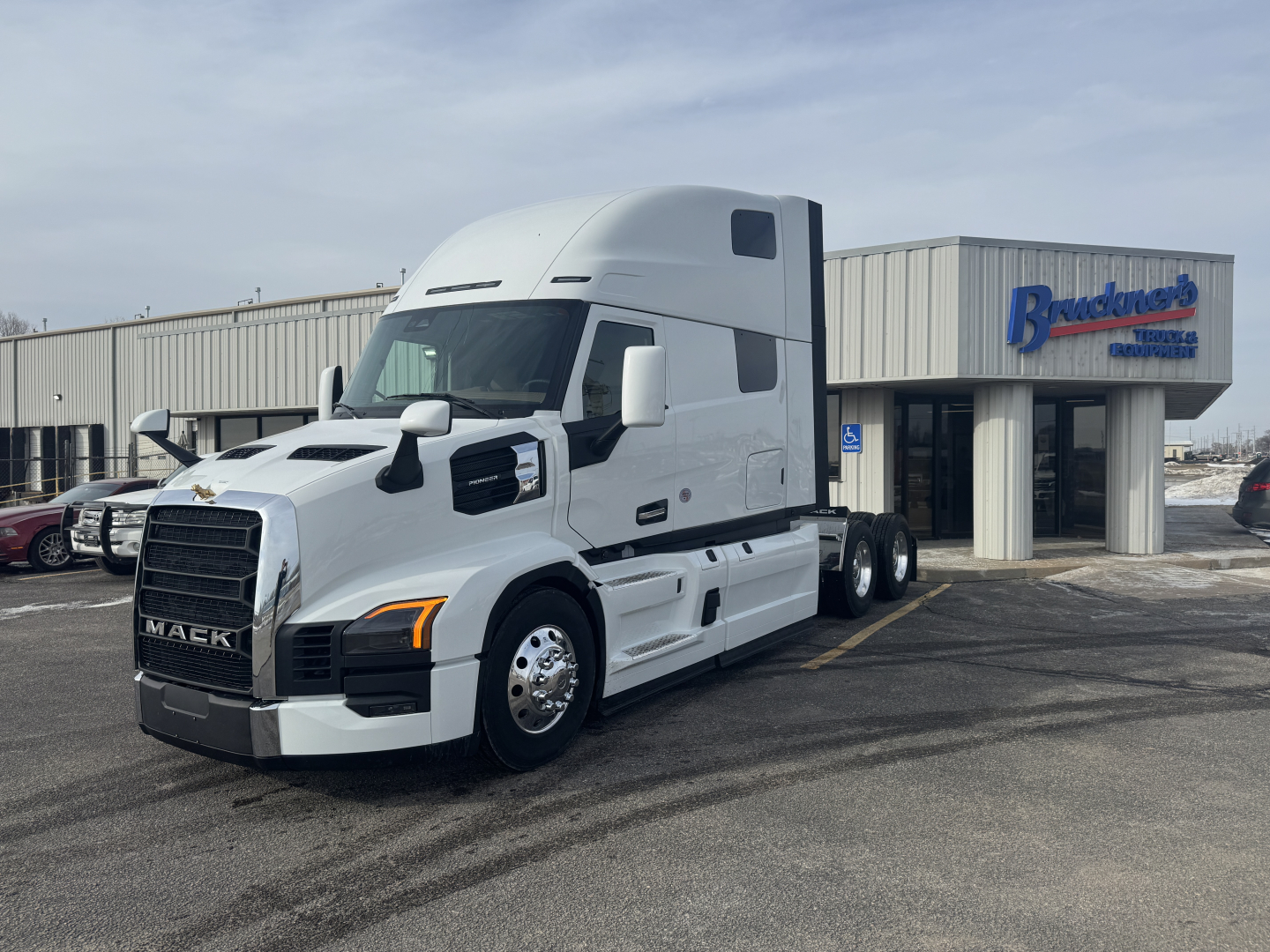 Truck image showing a white 2026 Mack PR64T76H tractor in a dealership lot with a blue Bodacious sign in background.