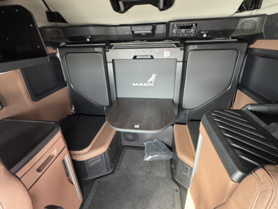 Front interior view of a 2026 Mack PR64T76H cab showing center table and storage compartments with Mack logo on the back wall.