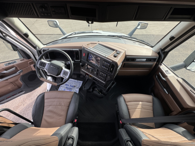 Cab interior of a Mack PR64T76H truck showing steering wheel, dashboard, and driver and passenger seats in view.