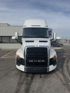 Front view of a white 2026 Mack PR64T76H conventional sleeper truck showing Mack grille, headlights, and emblem.