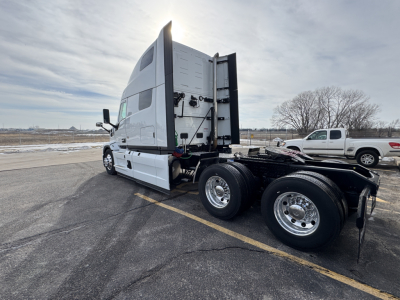 Truck chassis and cab of a 2026 Mack PR64T76H tractor with dual rear axles, side view showing sleeper cab and fuel/air lines near frame.