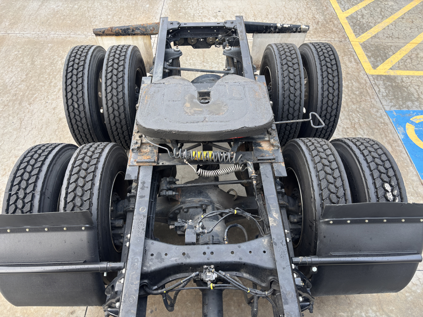 Truck chassis view showing dual rear axles and frame with suspension and drivetrain components visible.
