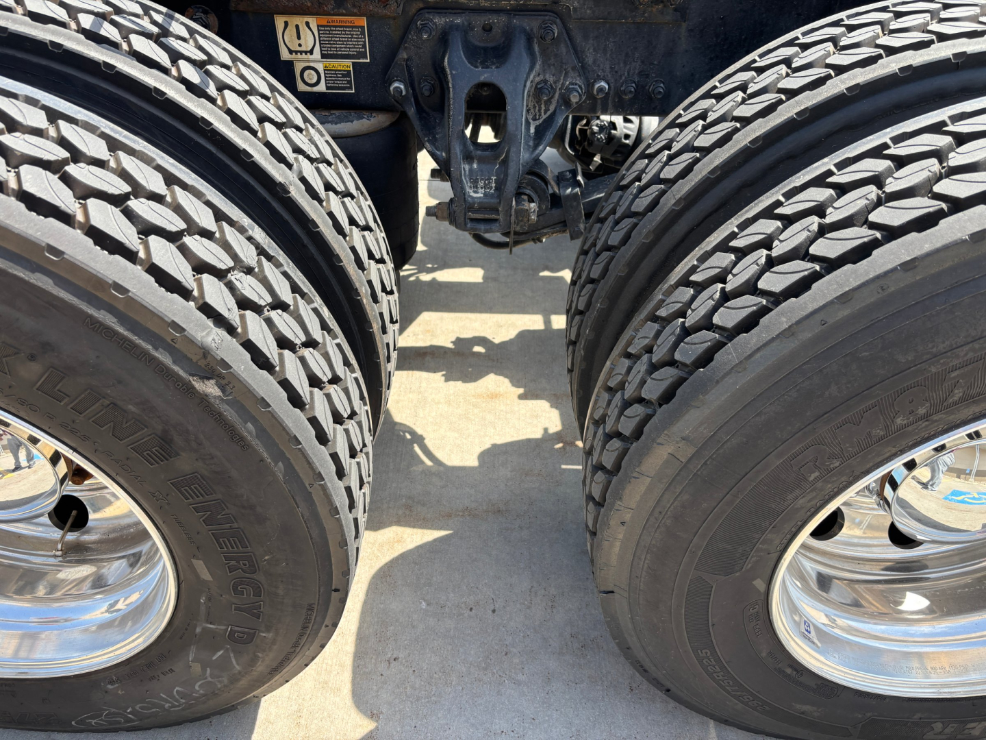 Kenworth T680 drivetrain area showing rear tractor tires, dual rear wheels, and chassis components.
