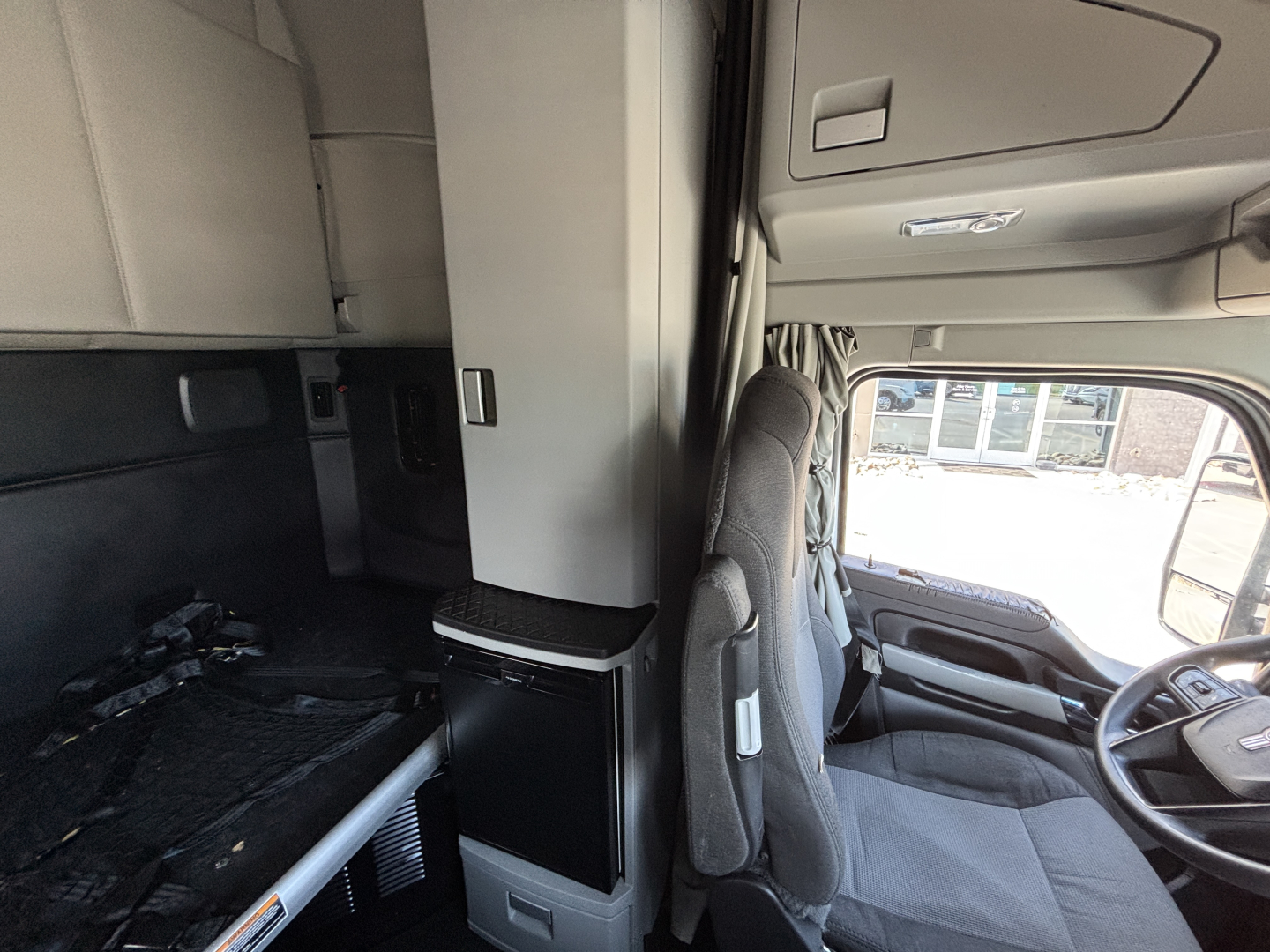 Kenworth T680 truck cabin interior view with driver seat and overhead storage.