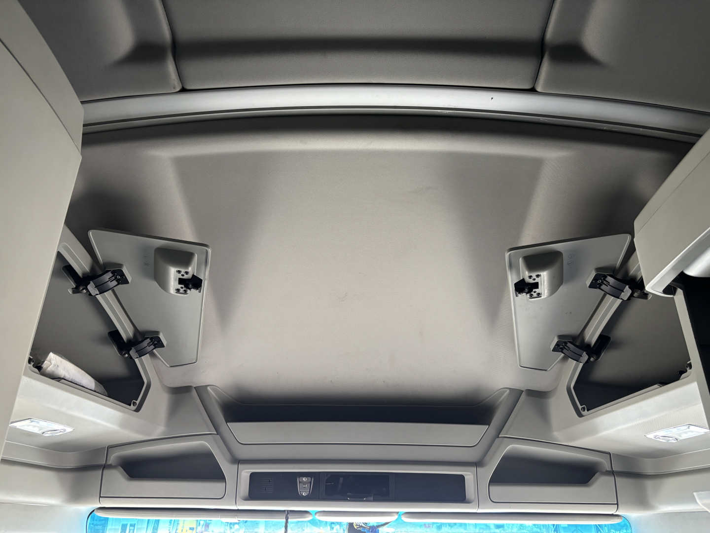 Cab interior ceiling view of a 2022 Kenworth T680 sleeper truck showing overhead storage compartments and sun visors.