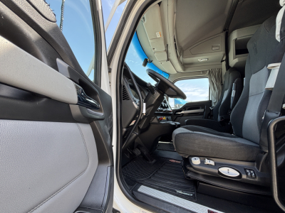 Kenworth T680 truck cabin interior view from open driver door, captain chair, dashboard, steering wheel, and entry steps visible.