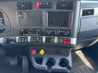 Kenworth T680 dash area showing vents, control switches, gauges, cup holders, and pedal area.