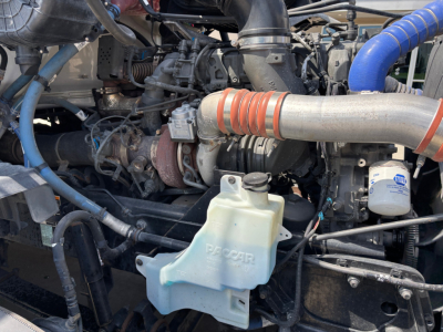 Kenworth T680 engine bay showing coolant reservoir and turbo hose with blue silicone hose.