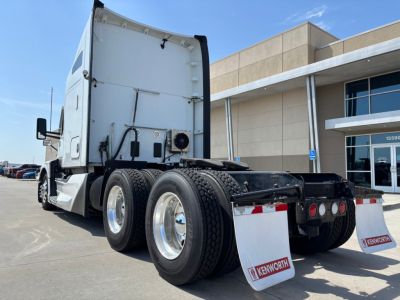 Kenworth T680 tractor rear view showing dual rear axles with tires and Kenworth mud flaps.