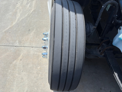 Diesel truck rear wheel and dual-tire setup on Kenworth T680; visible wheel, lug nuts, and part of suspension/axle area.