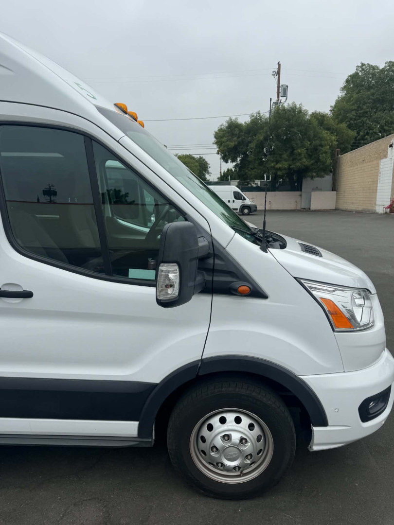 Ford Transit 350 HD XLT side/front view showing front wheel and passenger van door with mirrors and headlights.