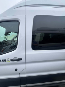 Ford Transit 350 HD XLT passenger van side view showing front door and windows with VIN label on door.