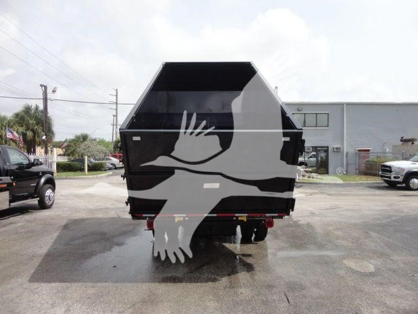 Tractor-trailer style dump bed on a Silverado 5500HD chassis showing a black dump bed with white bird graphic.