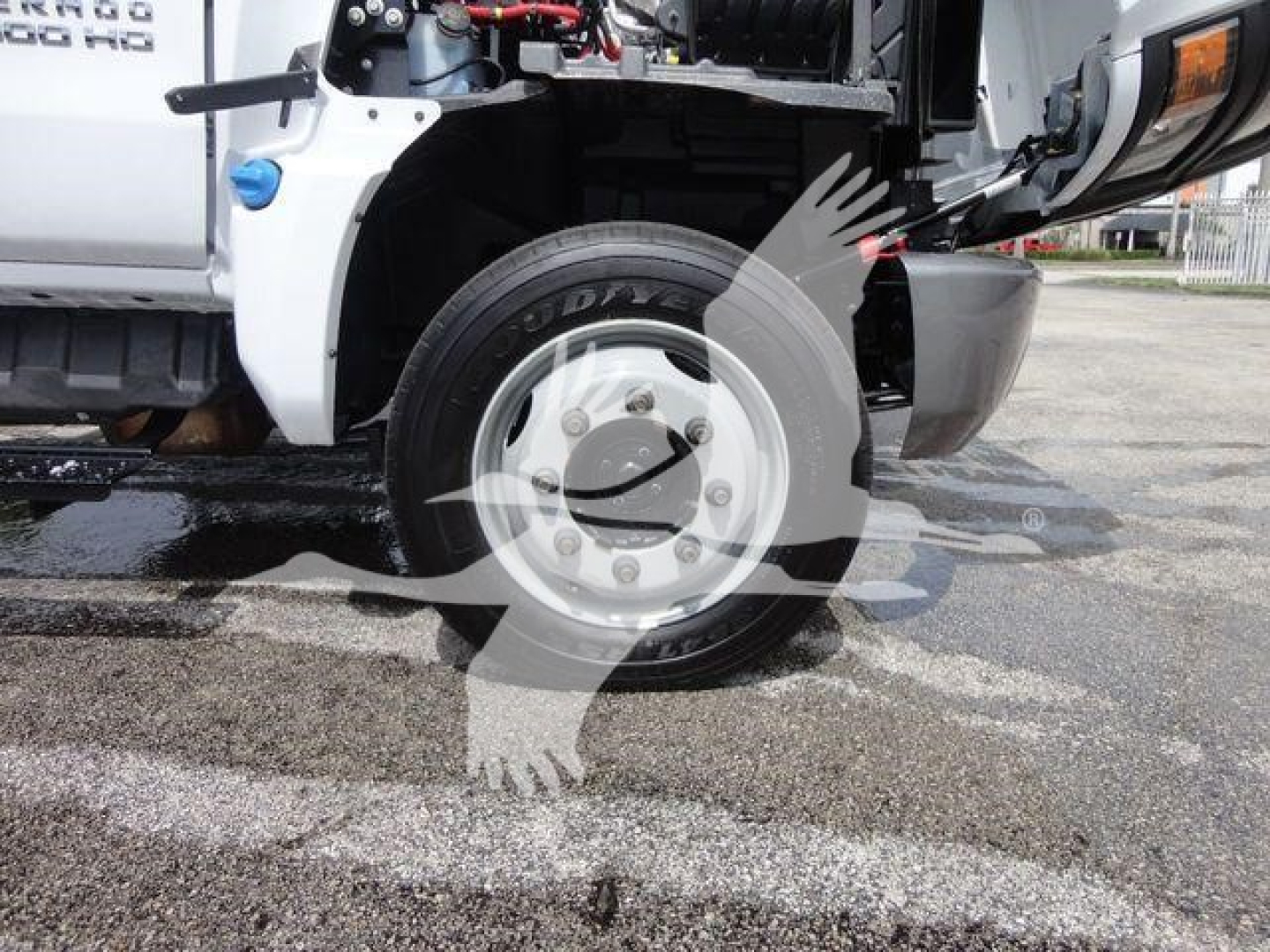 Front wheel and fender of a 2023 Chevrolet Silverado 5500HD roll-off truck showing tire, rim, and partial hydraulic components.