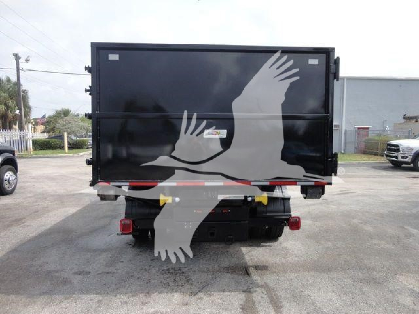 Rear view of a 2023 Chevrolet Silverado 5500HD rolloff truck, black dump bed, with taillights and bumper visible.